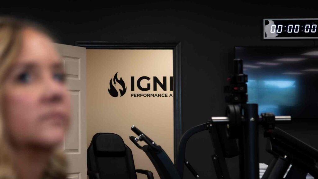 Ignite Performance and Health gym with strength-training equipment and a blurred woman in the foreground.