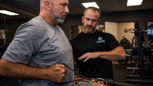 Derek guiding a client through a resistance-band exercise at Ignite Performance and Health.