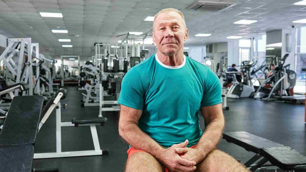 Older man seated in a gym, representing personalized strength, health, and performance planning.