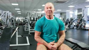 Older man seated in a gym, representing personalized strength, health, and performance planning.