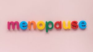 Colorful letters spelling “menopause” against a soft pink background.