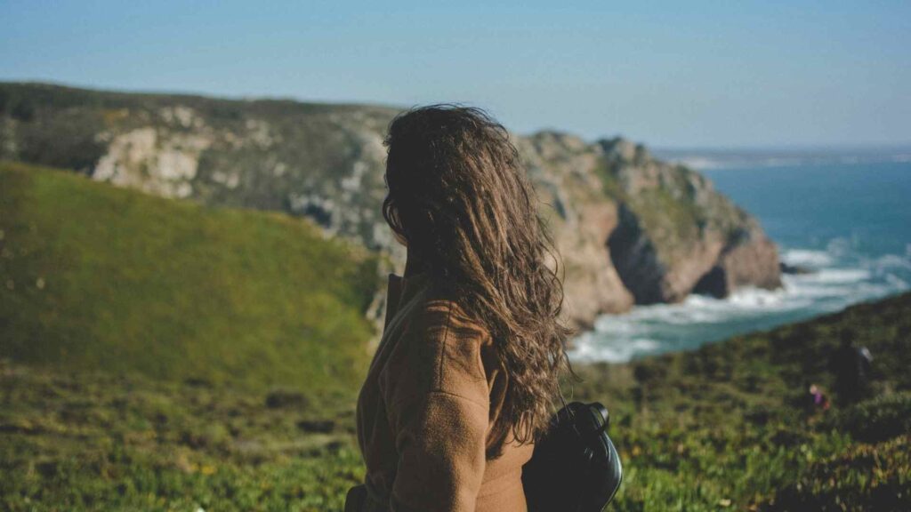 Woman overlooking coastal cliffs, representing strength, confidence, and healthy aging after 40.