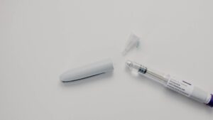 Tirzepatide injection pen and needle cap on a white surface.