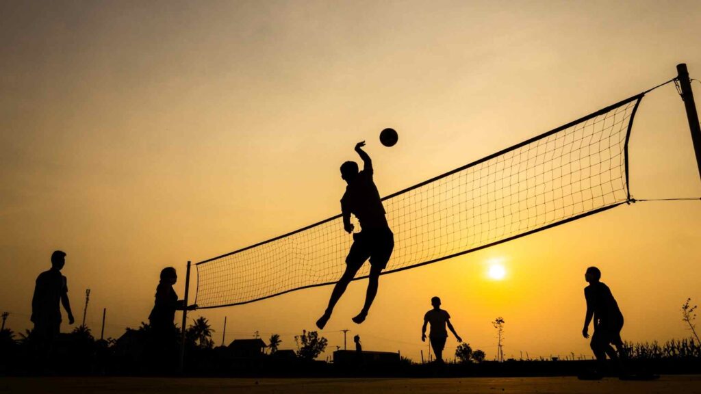 Silhouettes of people playing volleyball at sunset, representing movement, persistence, and renewed progress.