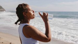 Woman drinking water after exercise on a beach.