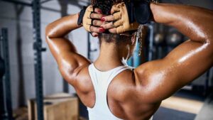 Woman displaying developed back and shoulder muscles after strength training in a gym.