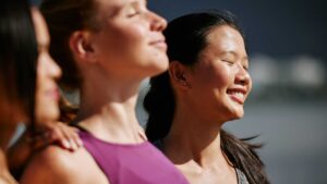 Group of women smiling together outdoors in warm sunlight.