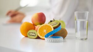 Fresh fruit, a measuring tape, and a glass of water representing nutrition and medical weight-loss support.